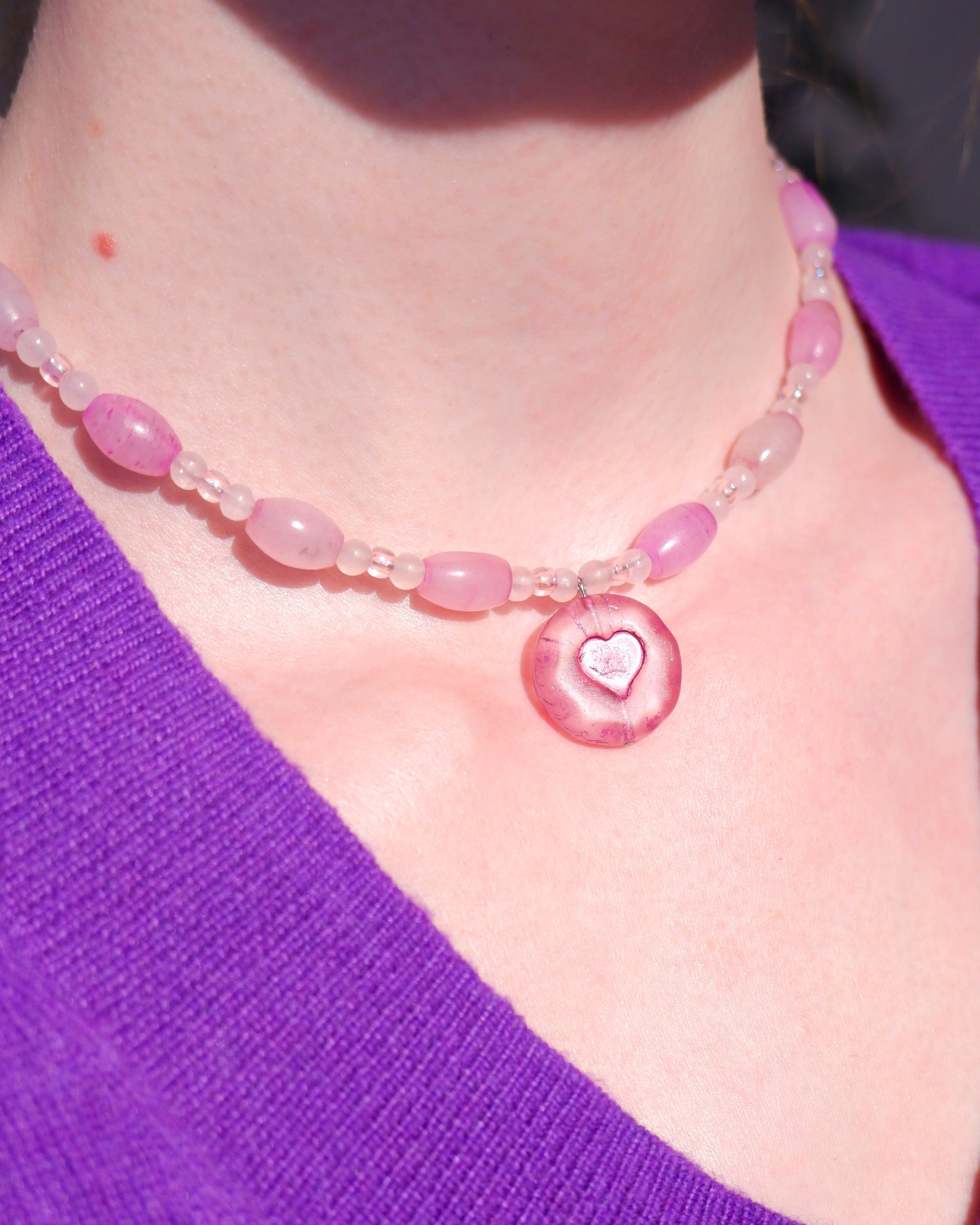 A necklace with a pink heart pendant and rose quartz beads