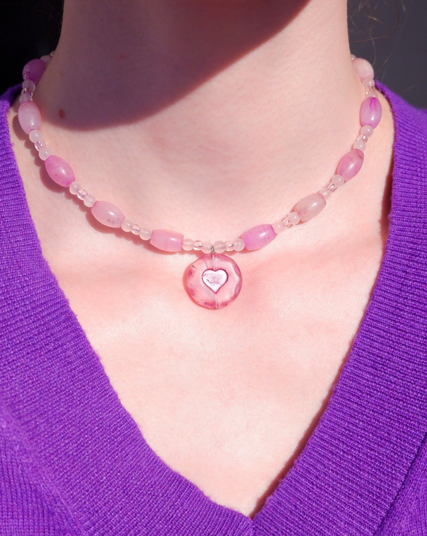 A necklace with a pink heart pendant and rose quartz beads