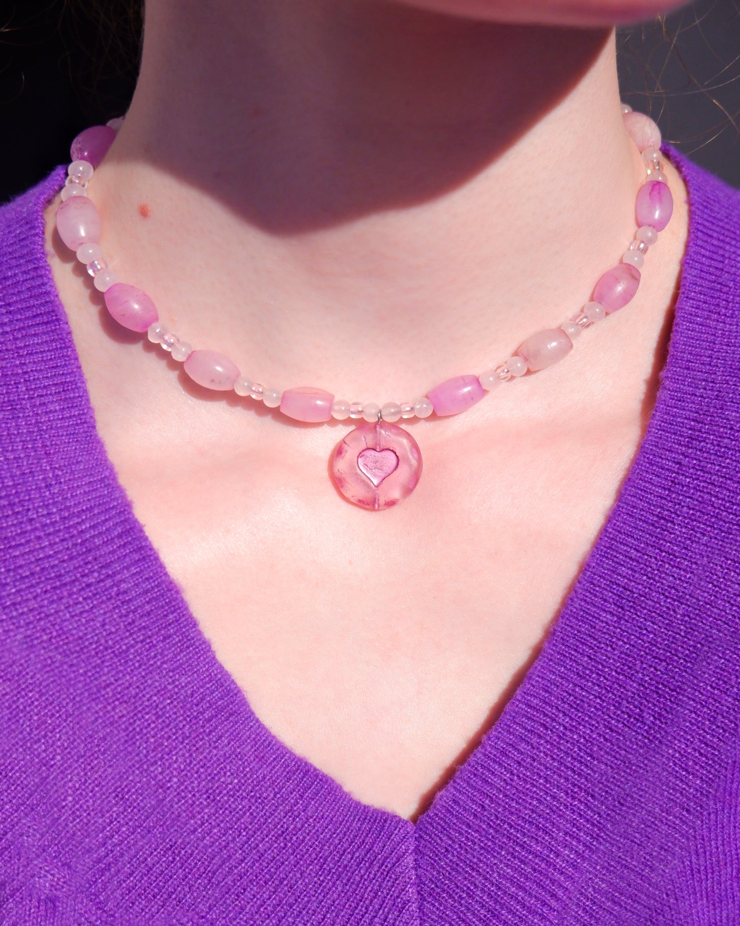 A necklace with a pink heart pendant and rose quartz beads