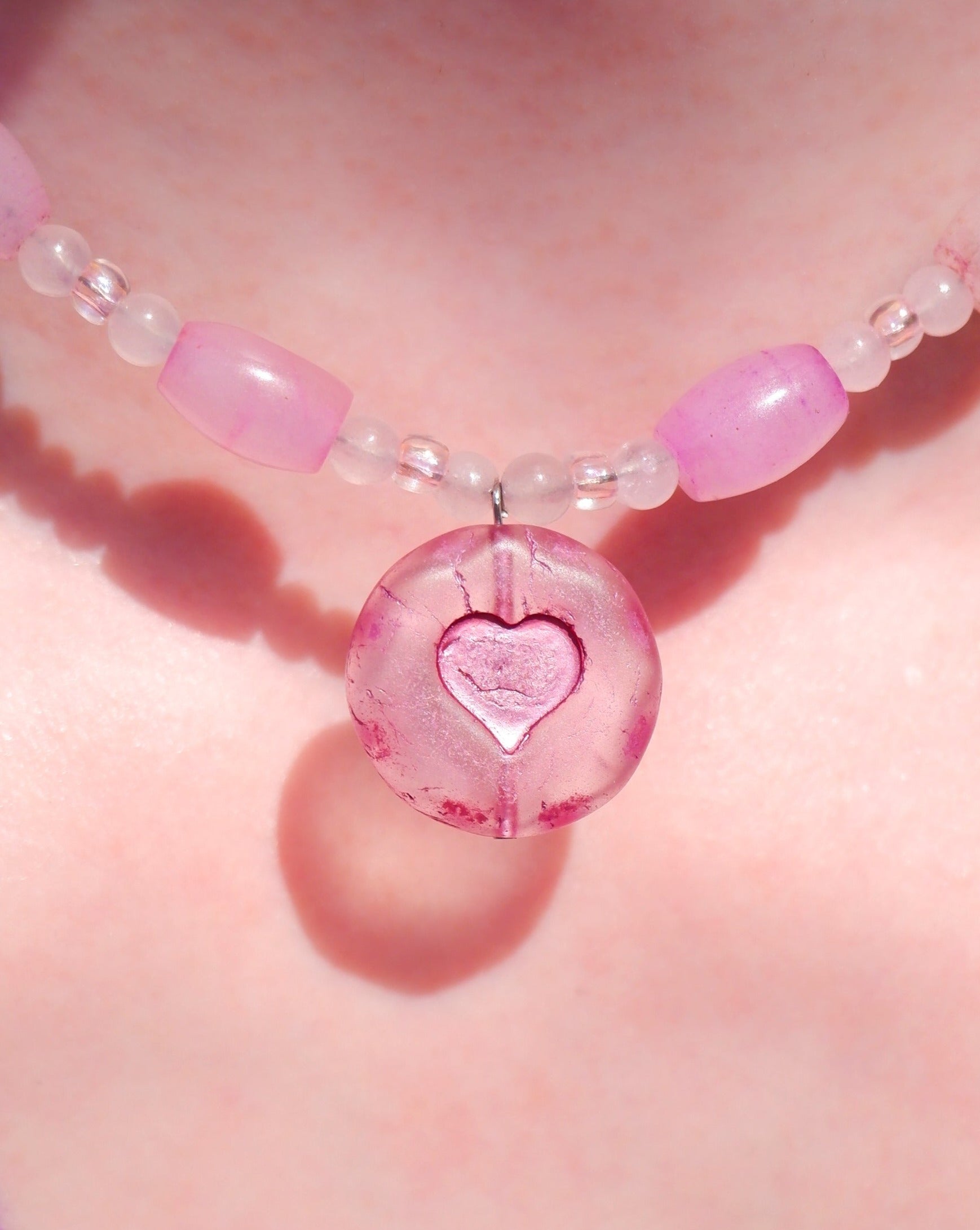 A necklace with a pink heart pendant and rose quartz beads