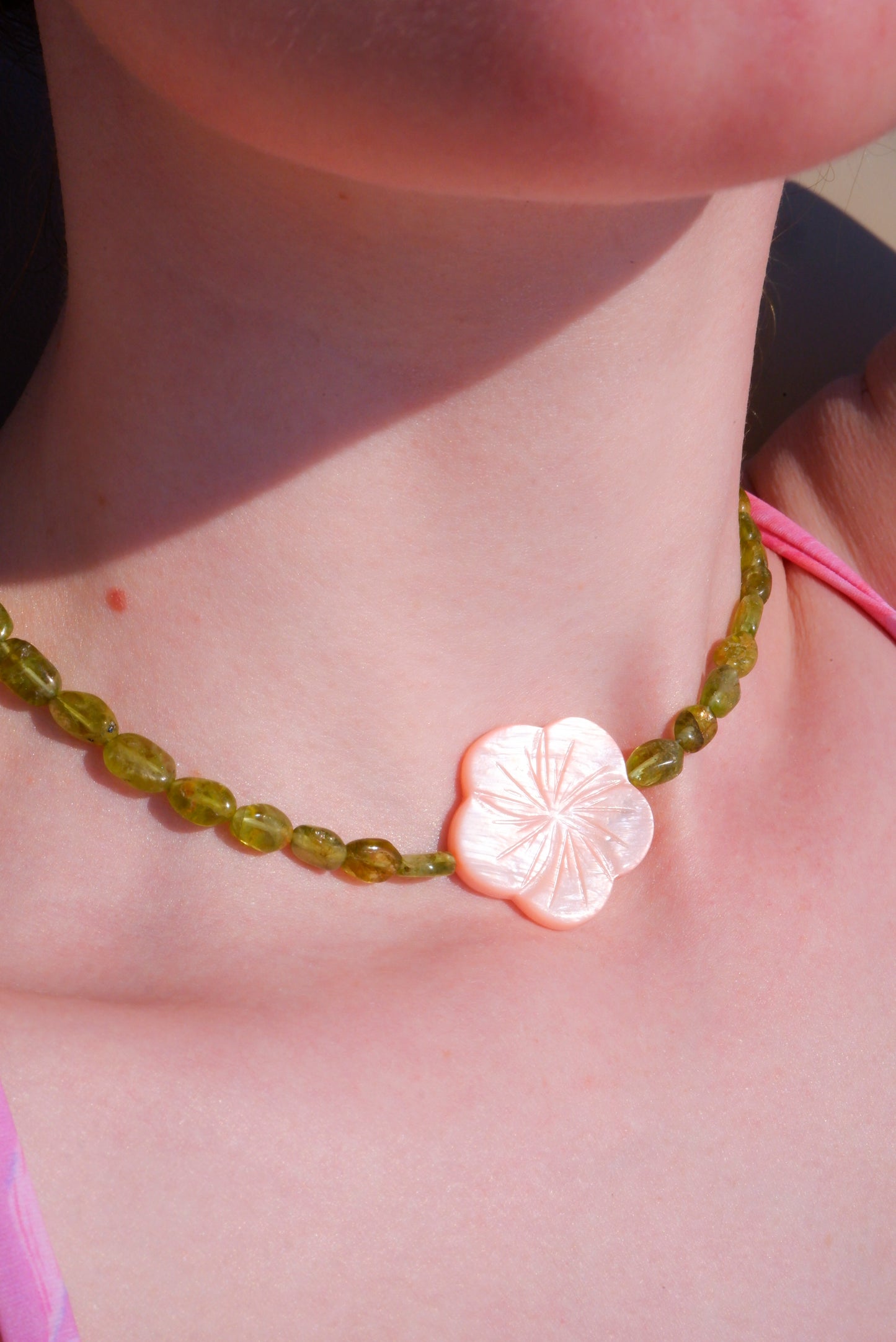 pink mother-of-pearl shell flower necklace on a strand of green peridot beads