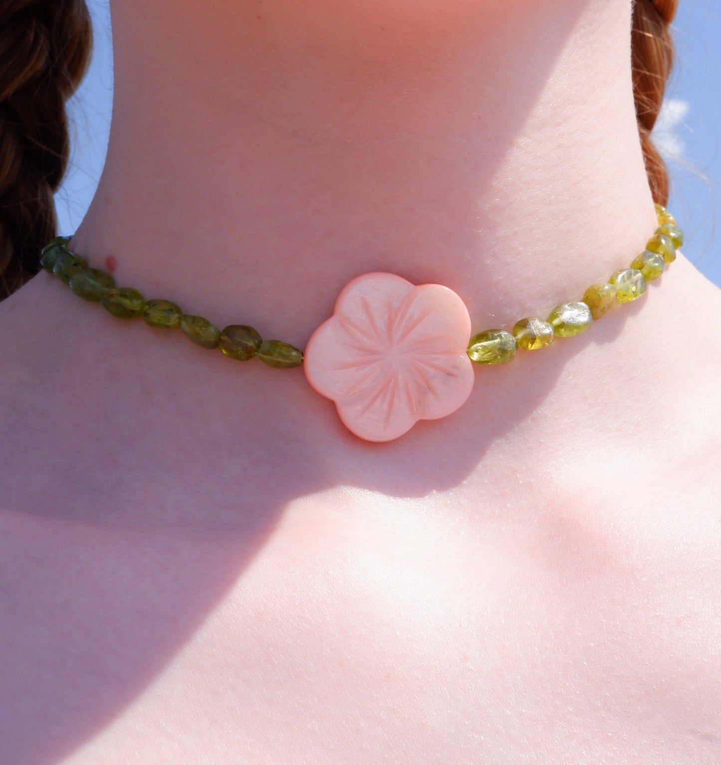 pink mother-of-pearl shell flower necklace on a strand of green peridot beads