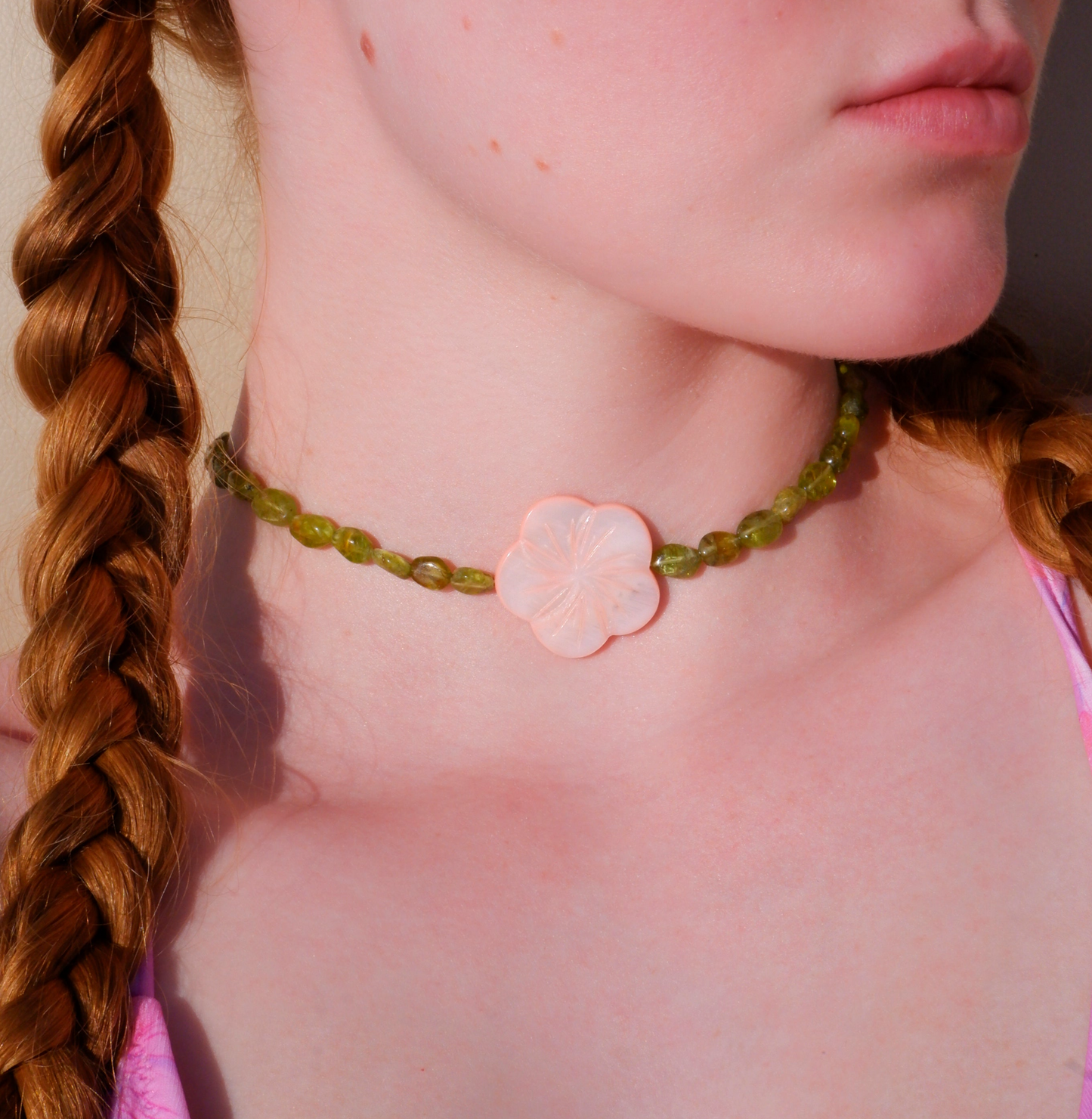 pink mother-of-pearl shell flower necklace on a strand of green peridot beads