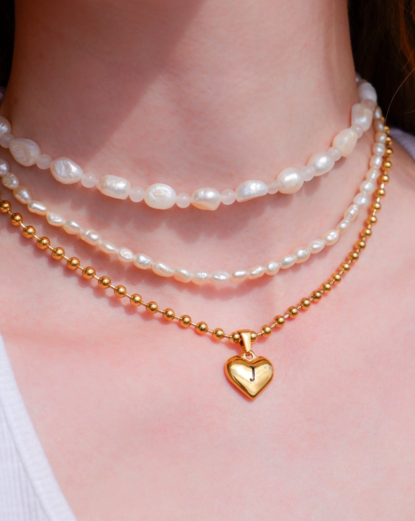 gold initial heart necklace layered with pearl necklaces