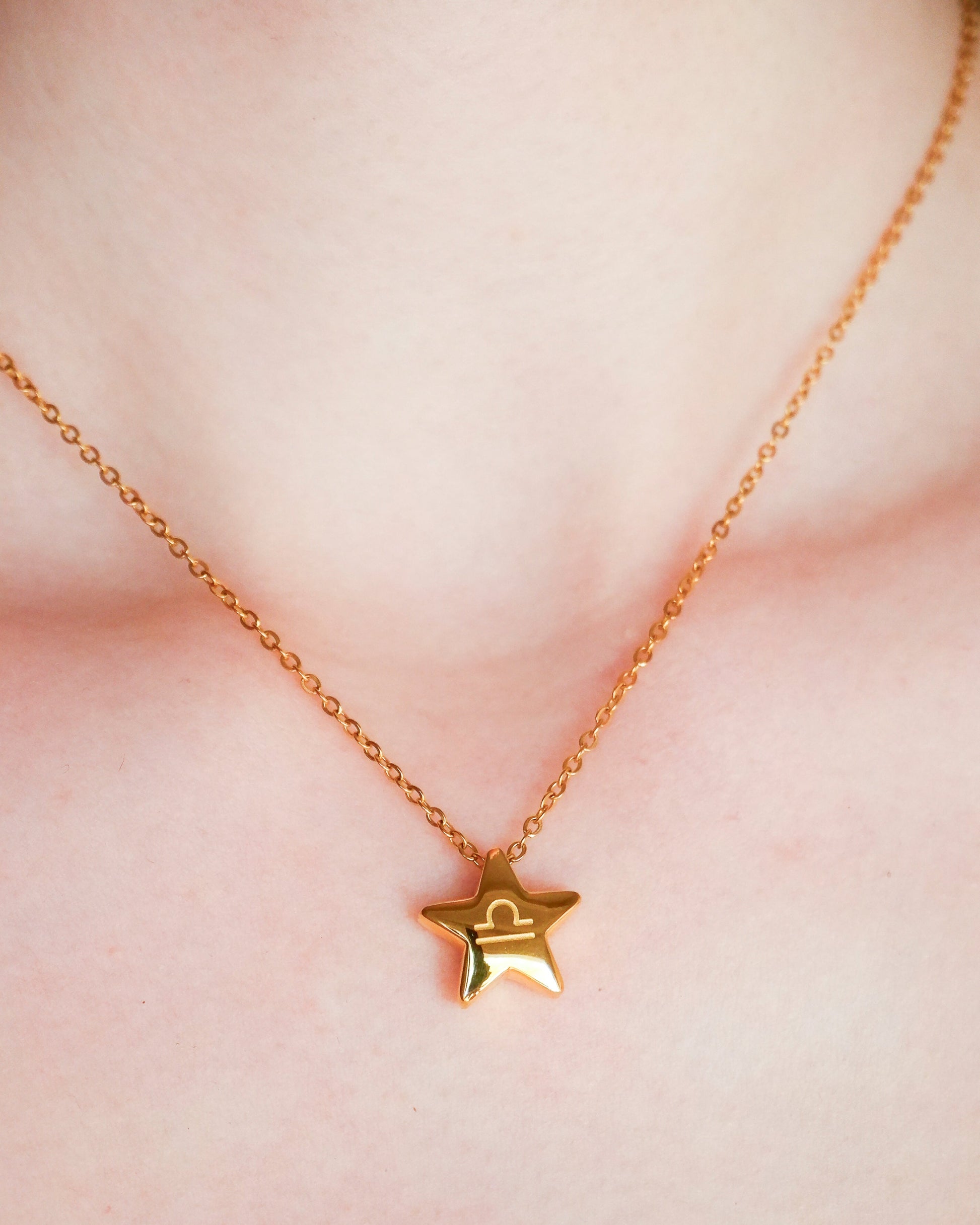 Gold star-shaped necklace on a person's neck against a neutral background