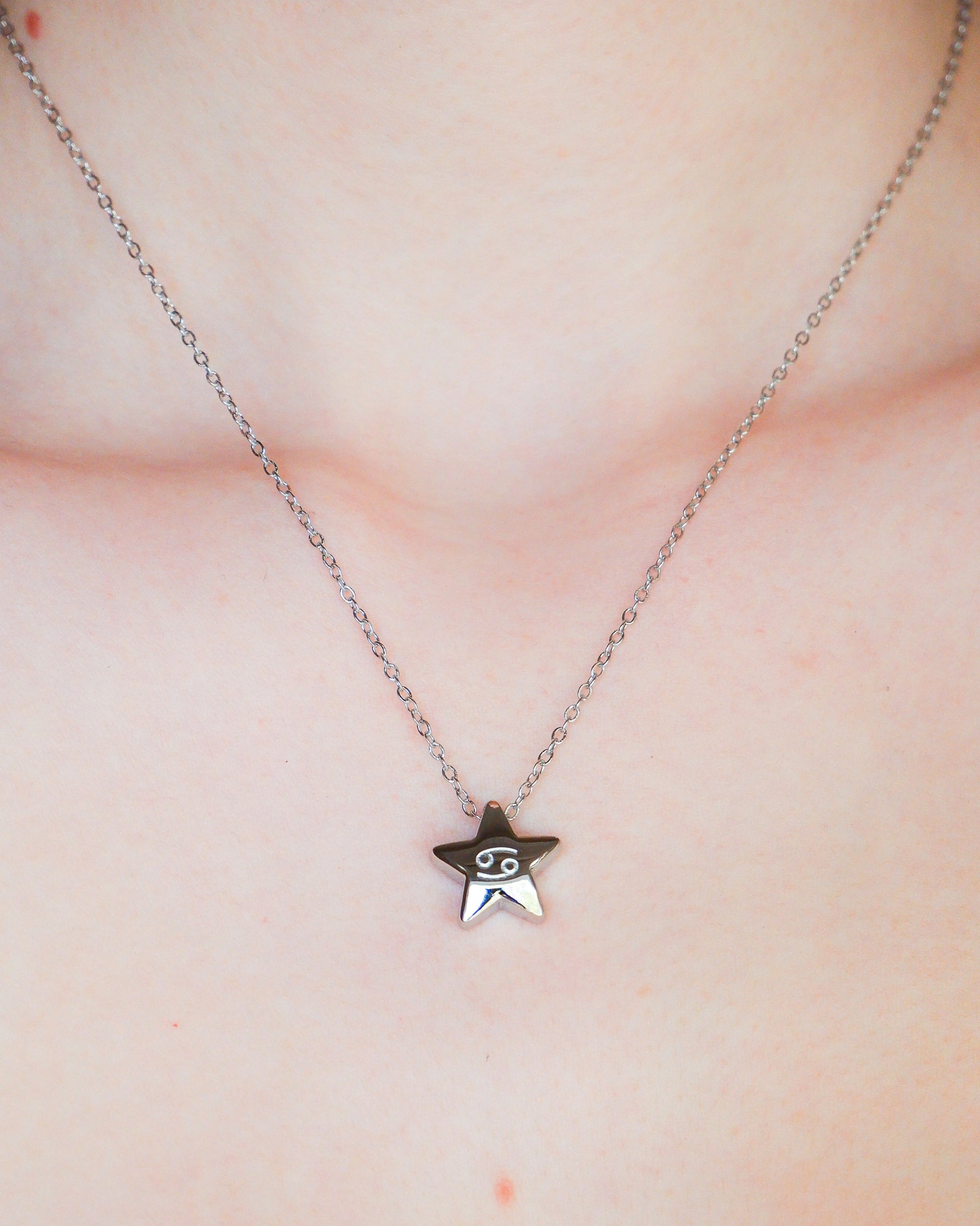 Star-shaped necklace with a small face pendant on a person's neck.