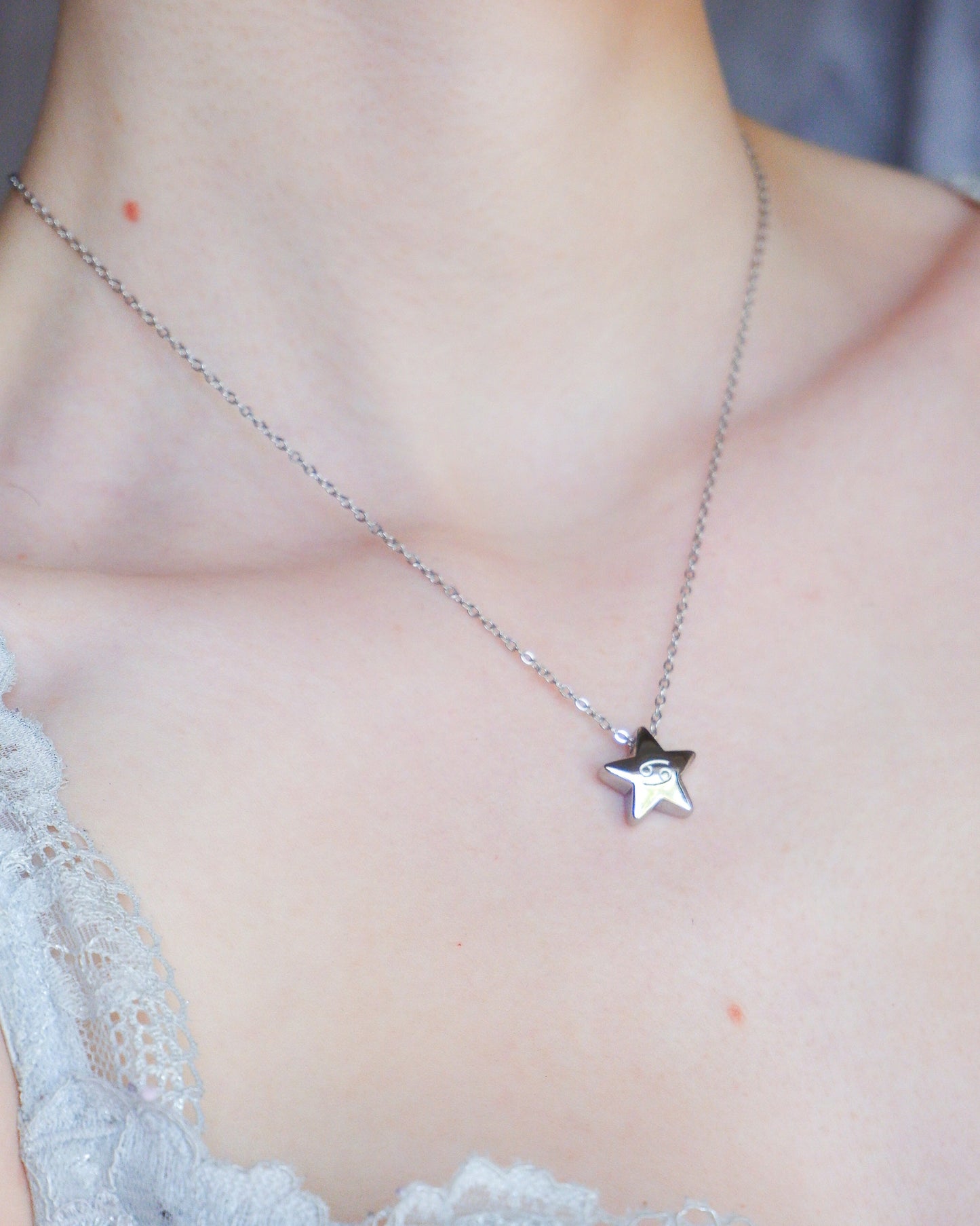 Star-shaped necklace on a person wearing a lace top.