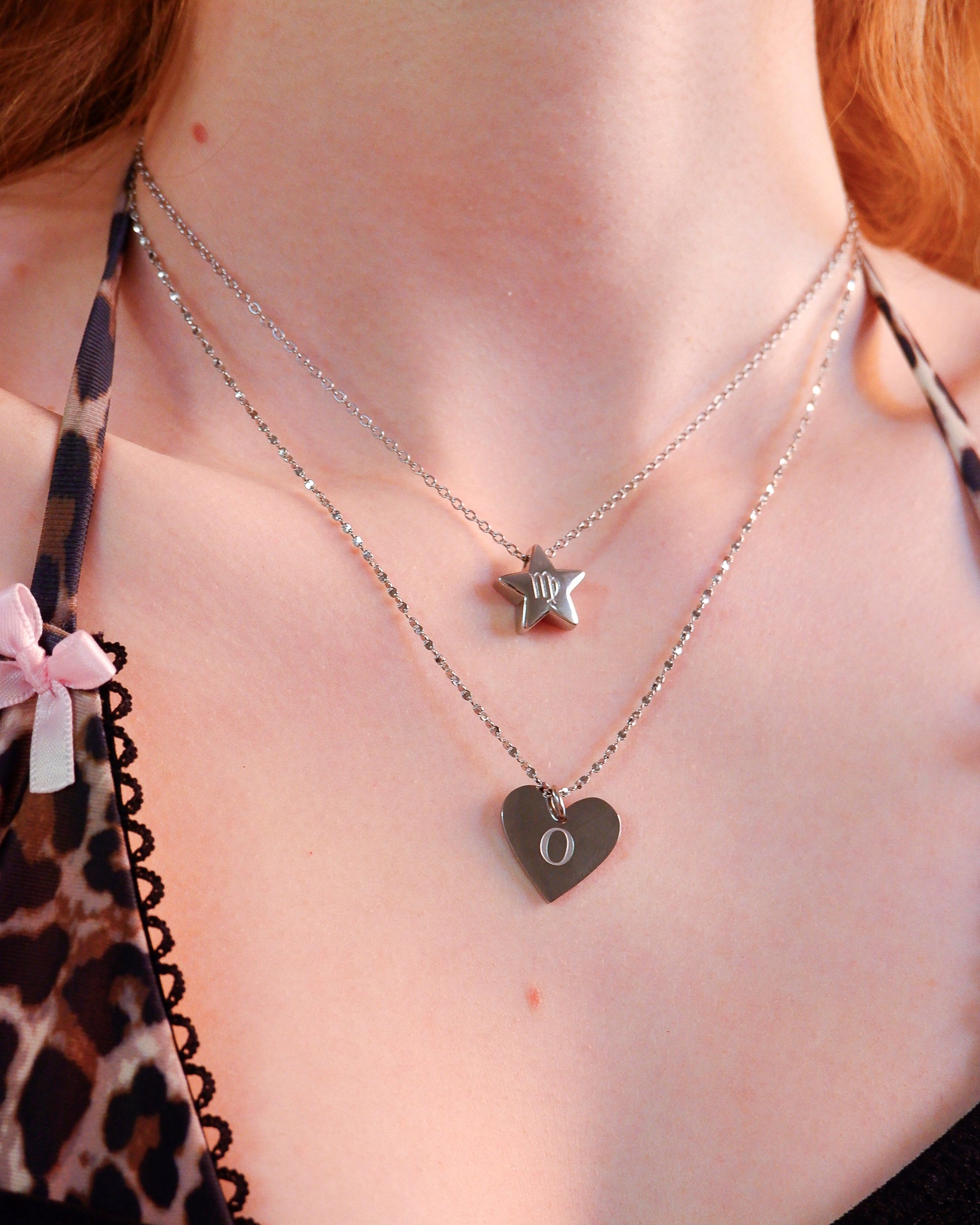 Close-up of a person wearing two necklaces with star and heart pendants.