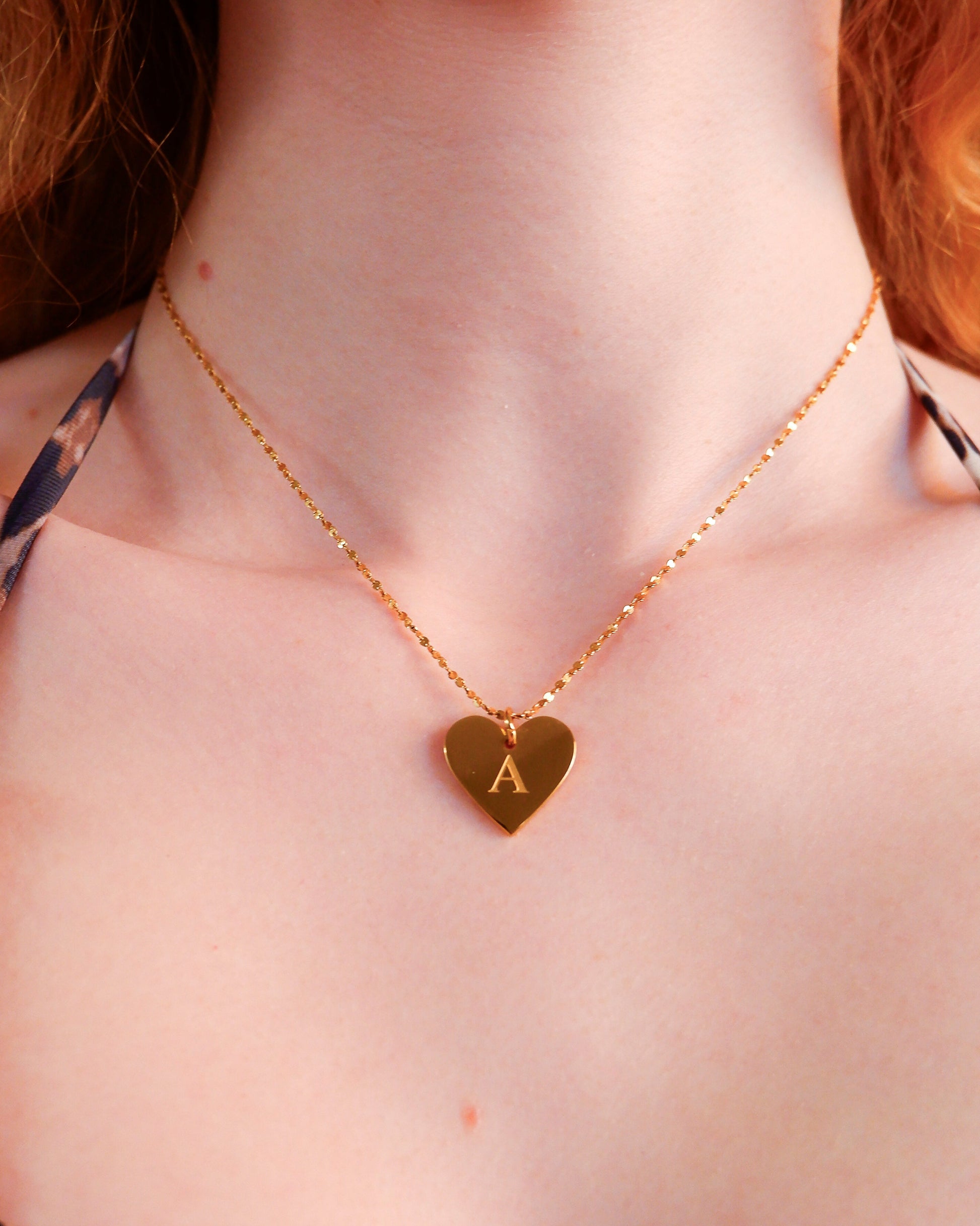 Gold necklace with a heart-shaped pendant on a person's neck