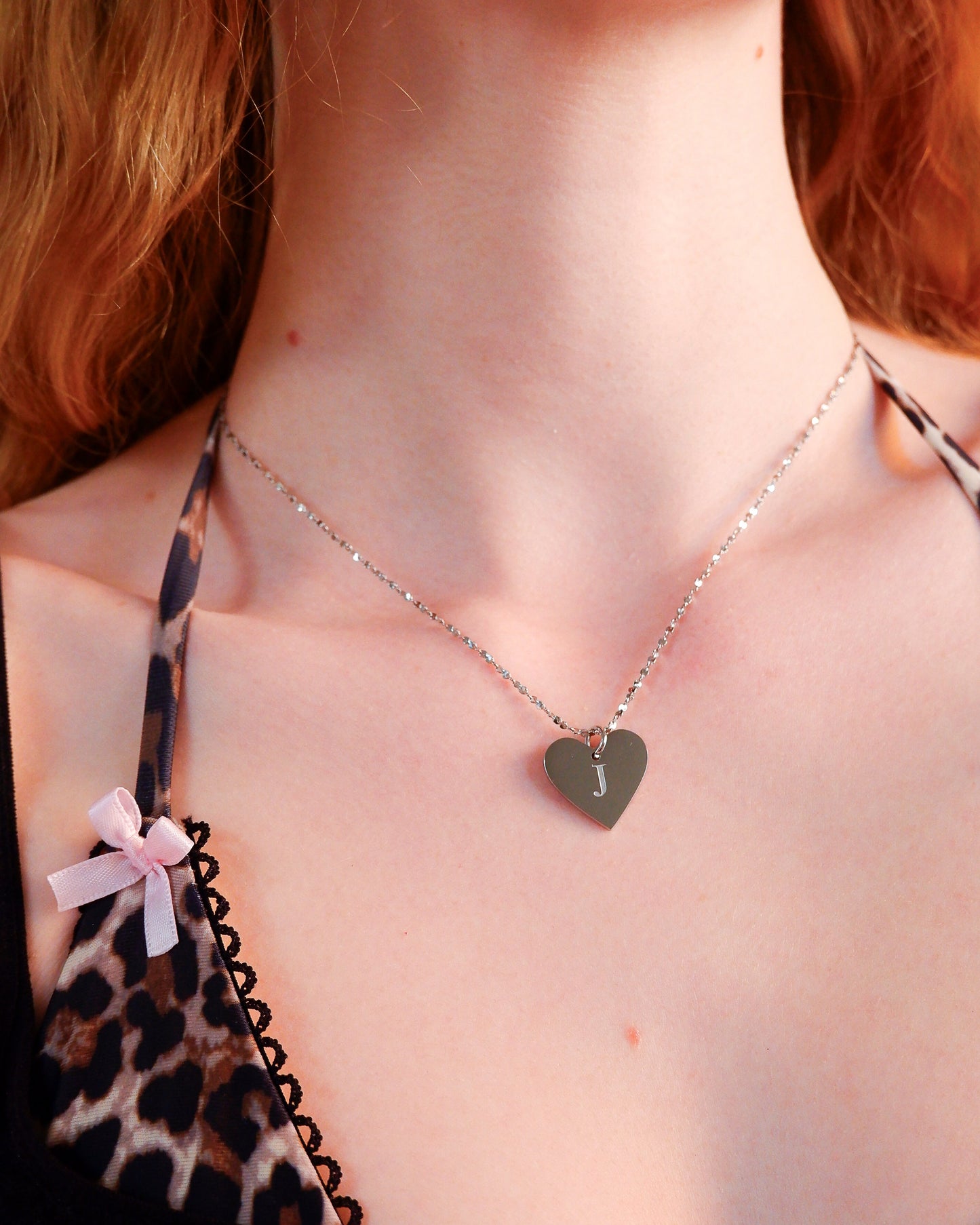 Necklace with a heart-shaped pendant worn by a person with red hair.