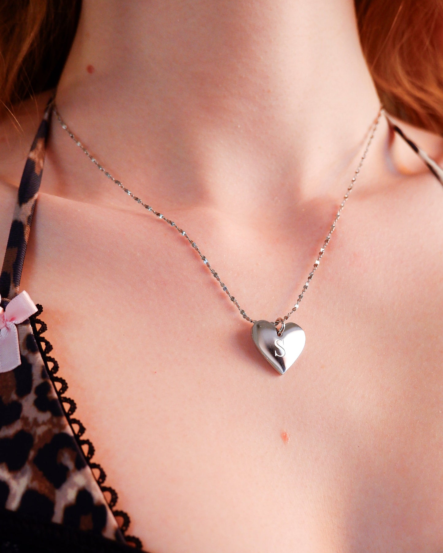 Heart-shaped pendant necklace on a person wearing a leopard print top.