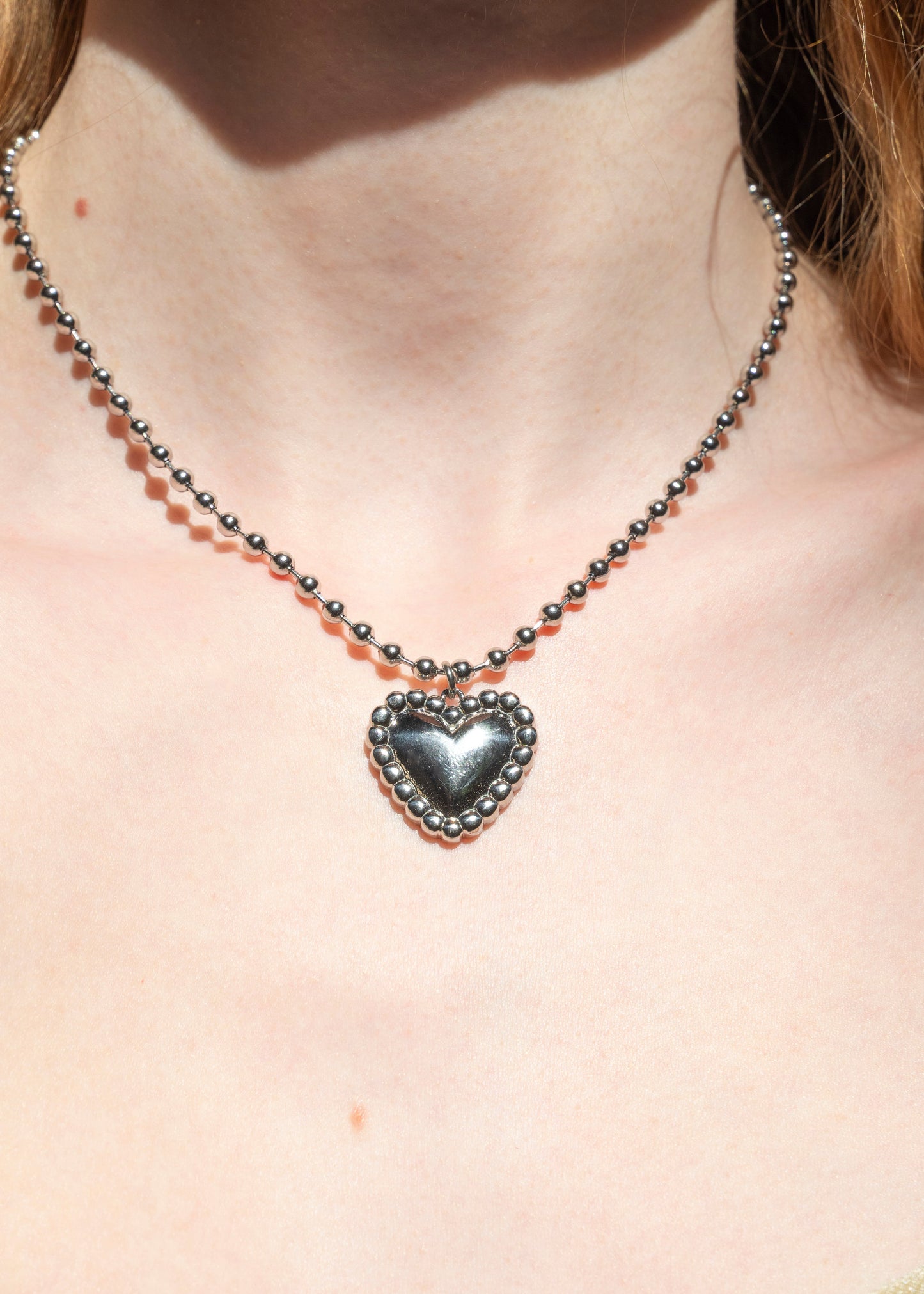 Necklace with a heart-shaped pendant on a person's neck