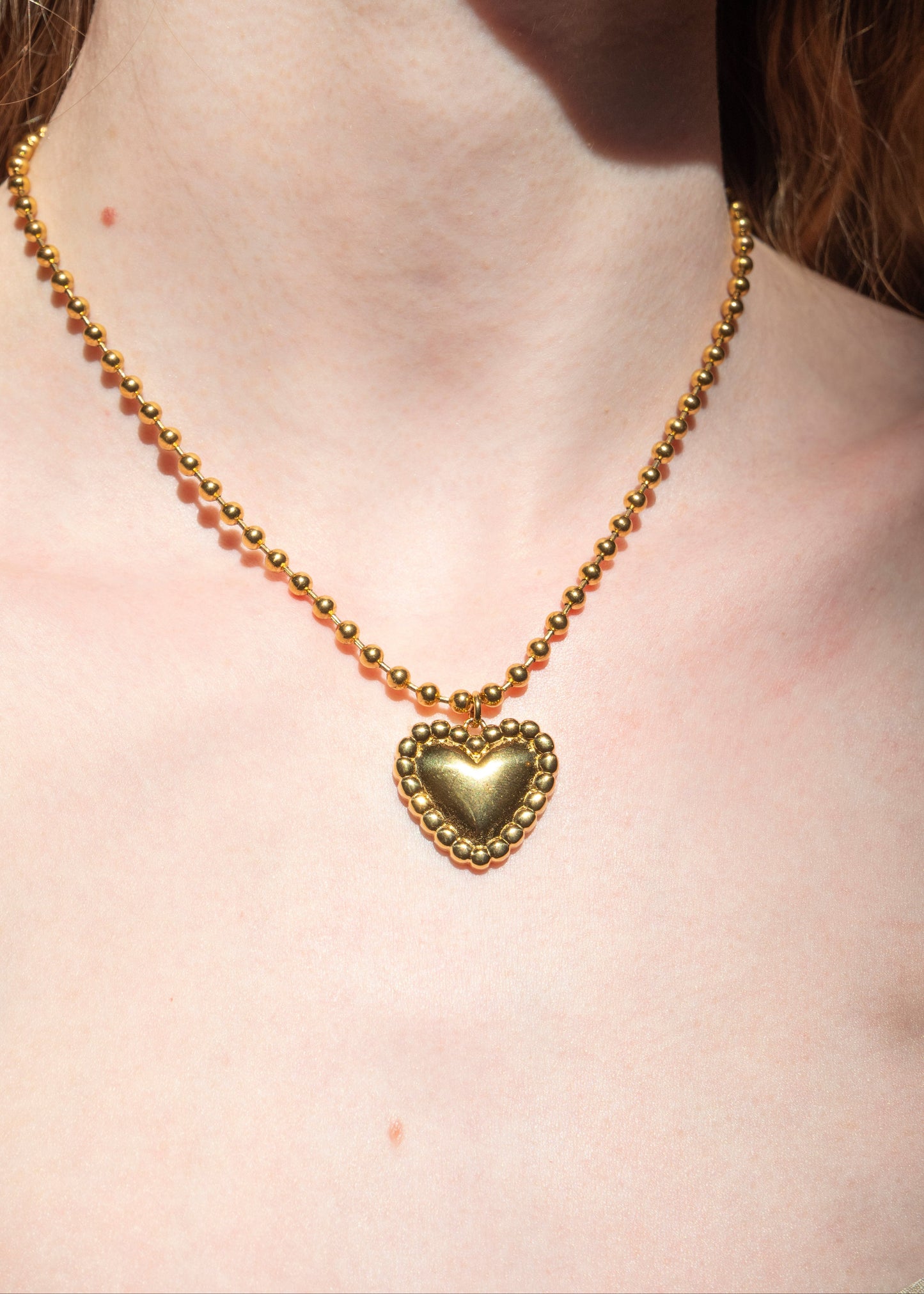 Gold necklace with a heart pendant on a person's neck
