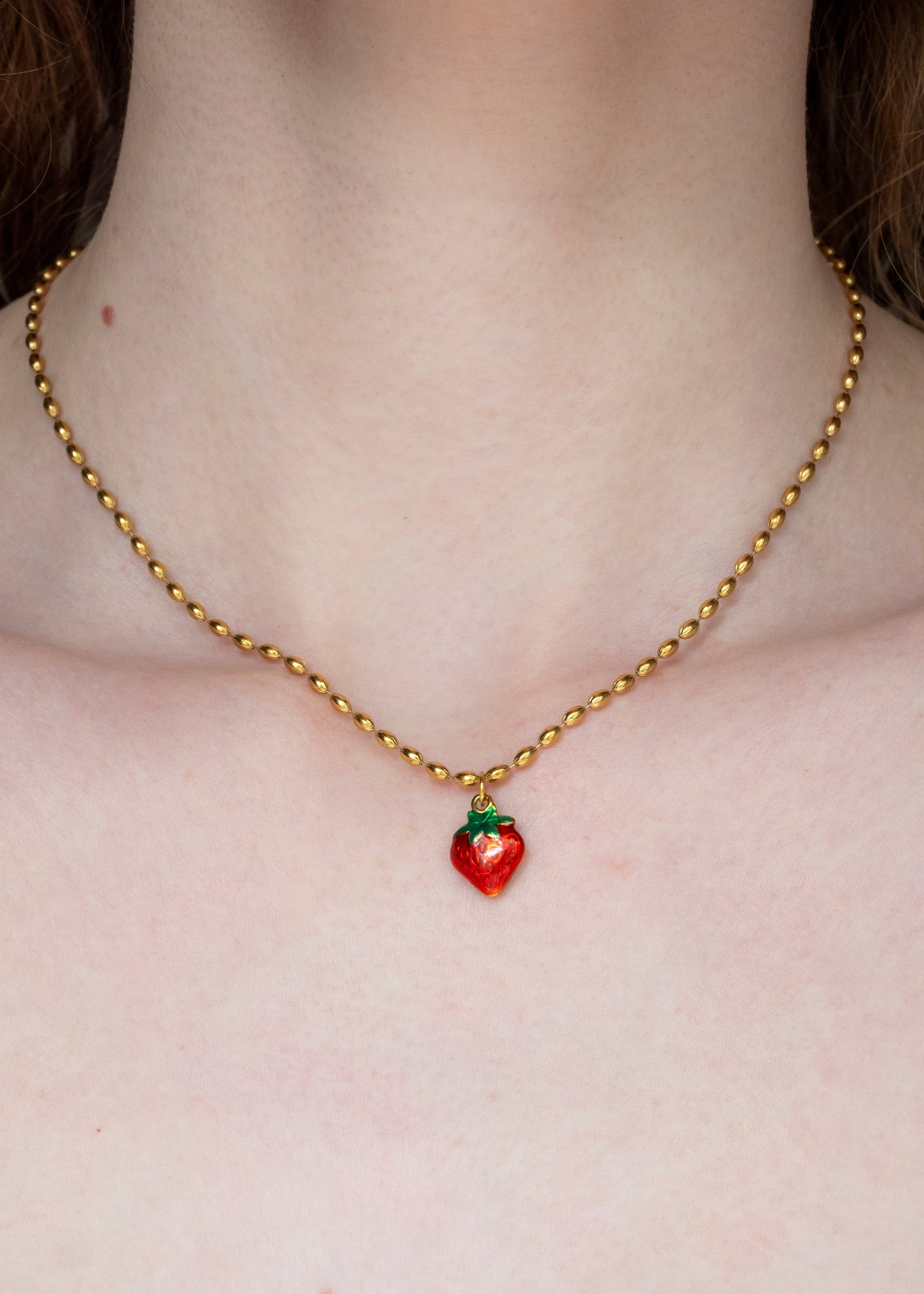 Necklace with a strawberry pendant on a plain background