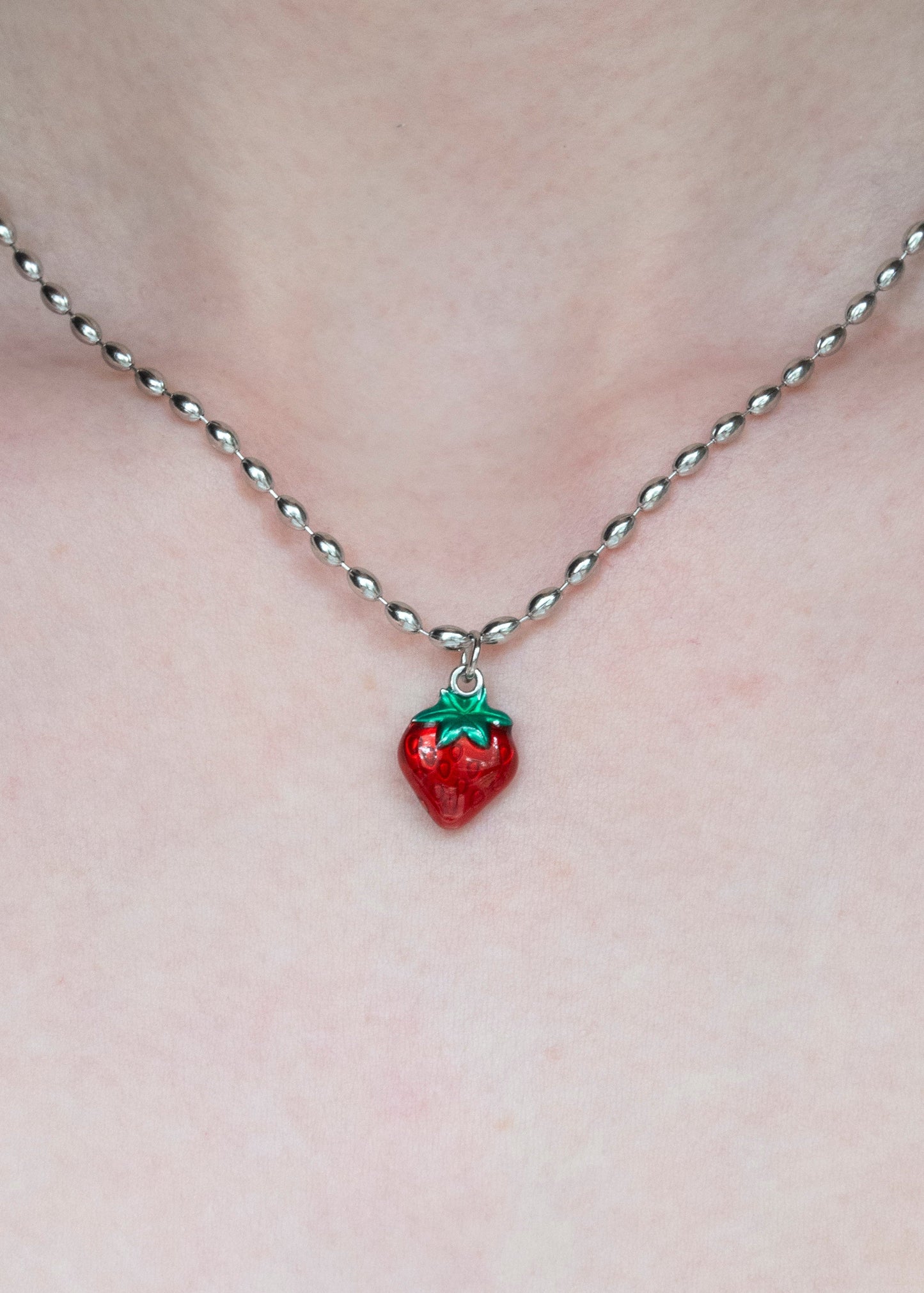 Necklace with a strawberry pendant on a plain background
