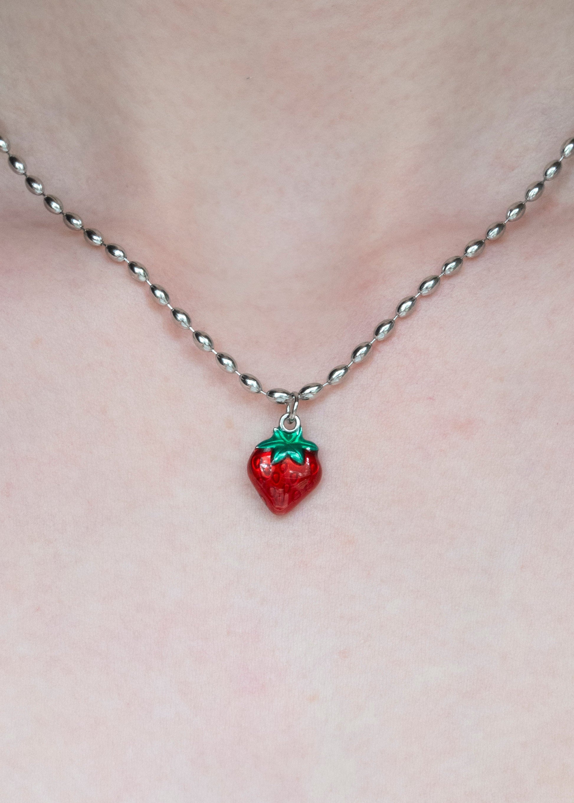 Necklace with a strawberry pendant on a plain background
