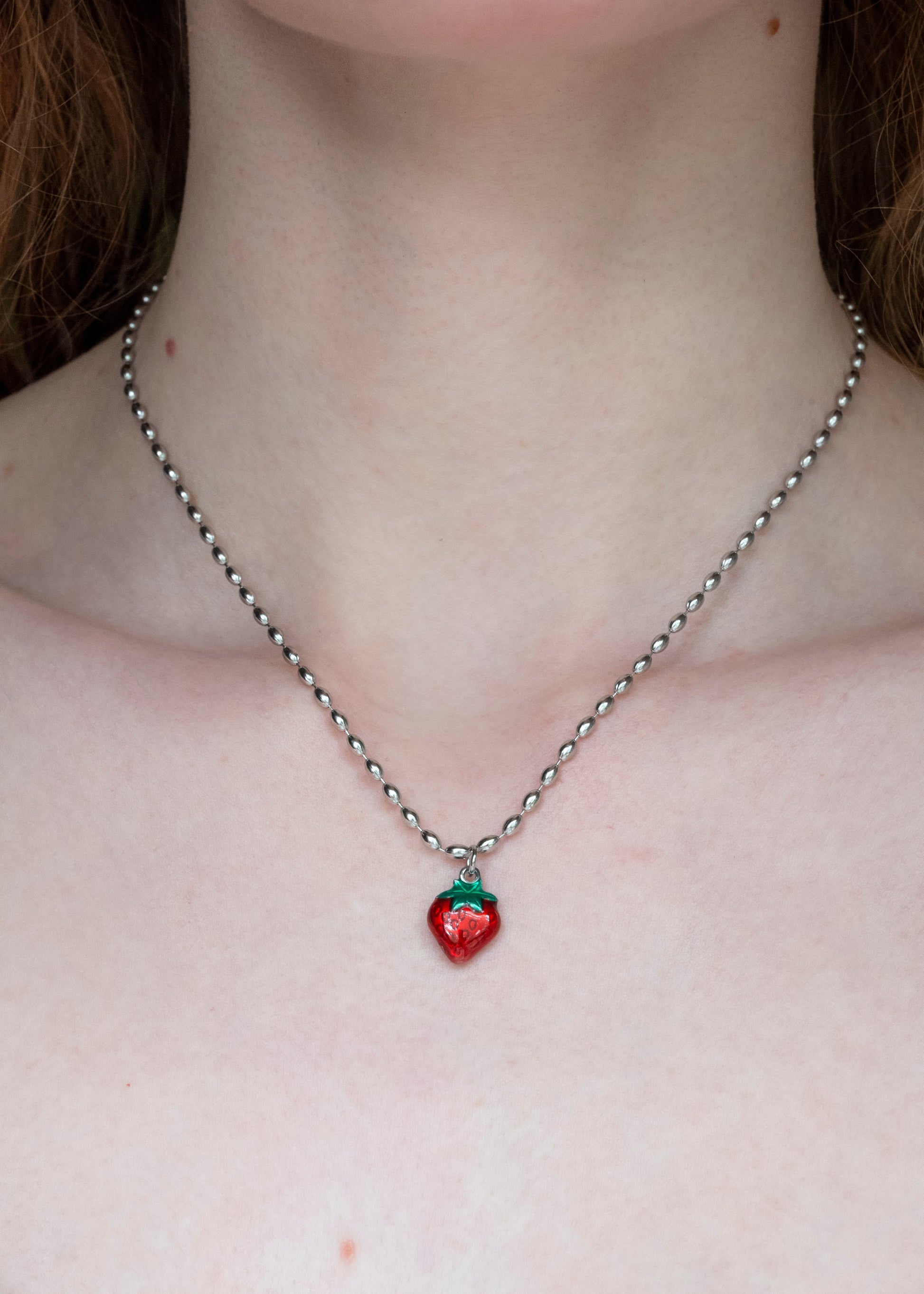 Necklace with a strawberry pendant worn by a person