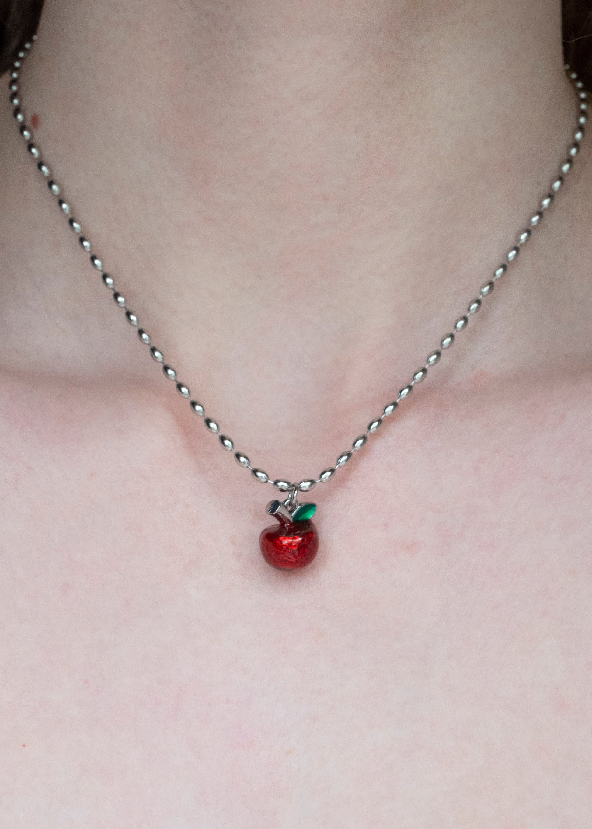Necklace with a red apple pendant on a plain background