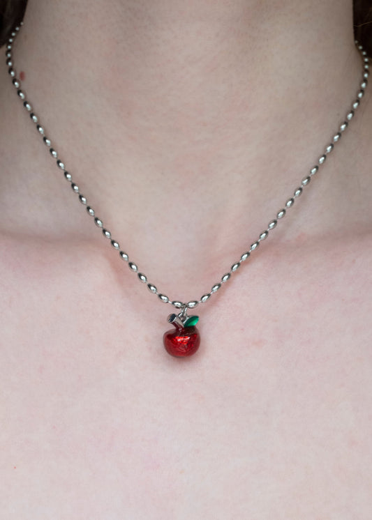 Necklace with a red apple pendant on a plain background